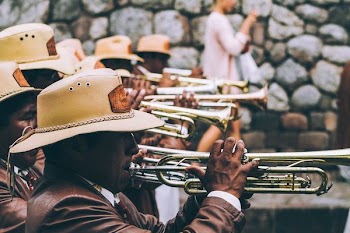group of musician performing near gray wall