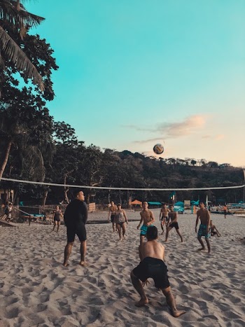 Group of People Playing Beach Volleyball on Shore