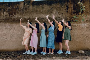 Group of Women Standing Infront of Brown Wall