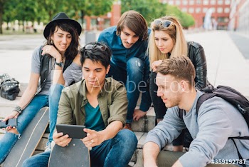 Group of young friends watching smartphone while sitting outdoors