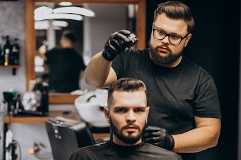 Hairdresser at a barber shop styling hair of a client Free Photo