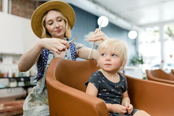 Hairstylist giving a haircut to an adorable… | Free stock photo | High Resolution image