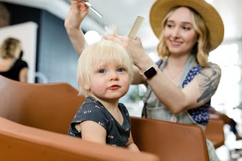 Hairstylist giving a little kid a haircut  | Free stock photo | High Resolution image
