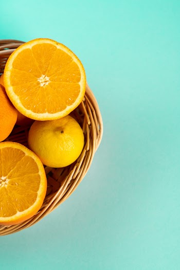 Half orange and lemon in a wicker basket on the table Free Photo