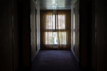 hallway leading to window covered by brown window curtain