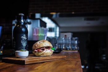hamburger on chopping board near ceramic bowl and glass bottle
