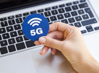 Hand holding 5g sticker above laptop Free Photo