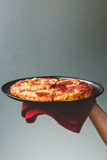 Hand Holding Oven Cooked Pizza