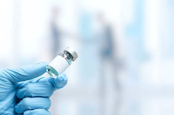 Hand in medical glove holding a vaccine vial