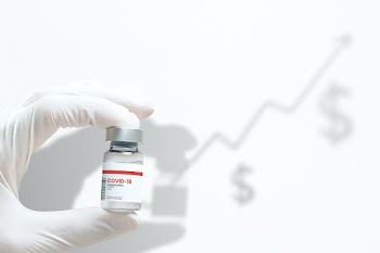 Hand in medical glove holding a vaccine vial