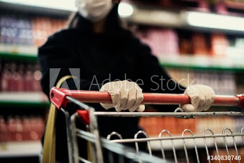Hand wearing a latex glove while pushing a shopping cart to prevent coronavirus contamination
