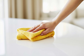 Hand Wiping a Glossy White Table with Microfiber Cloth