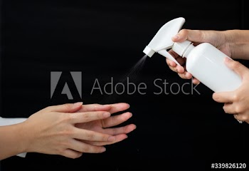 Hands being sprayed by white spray bottle