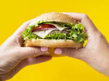 Hands holding a burger on yellow background Free Photo