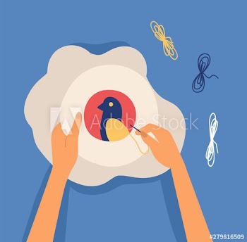 Hands making decorative craftwork - embroidering bird on hoop