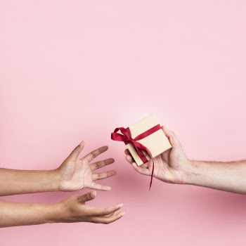 Hands receiving a small wrapped gift with ribbon Free Photo