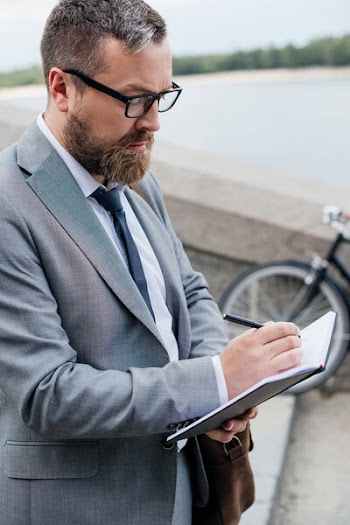 Handsome businessman in suit writing in diary
