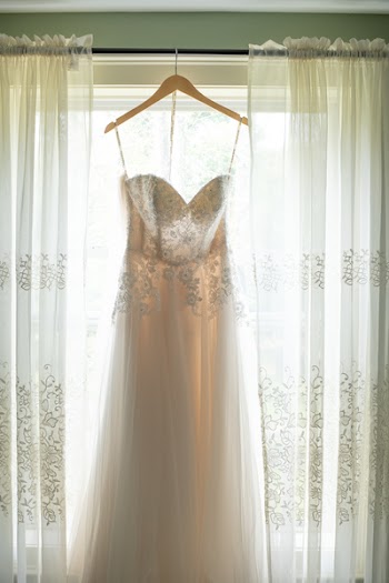 Hanged White Applique Corset Wedding Gown in Between White Window Curtain Inside Room