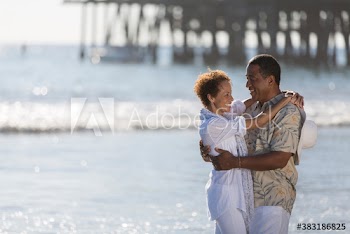 Happy active senior couple hugging on sunny ocean beach