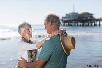 Happy active senior couple hugging on sunny ocean beach