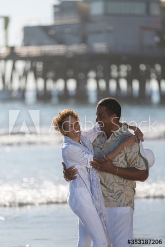 Happy active senior couple hugging on sunny ocean beach