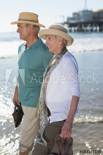 Happy active senior couple wading in ocean surf