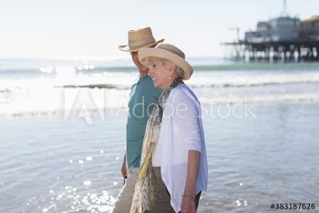 Happy active senior couple wading in sunny ocean