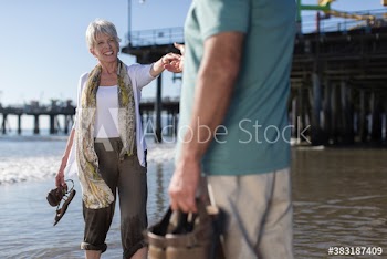 Happy active senior couple wading in sunny ocean surf