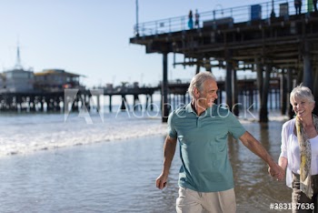 Happy active senior couple wading in sunny ocean surf