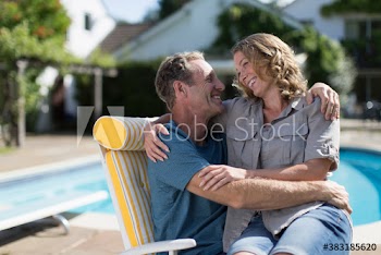 Happy affectionate couple hugging on sunny patio