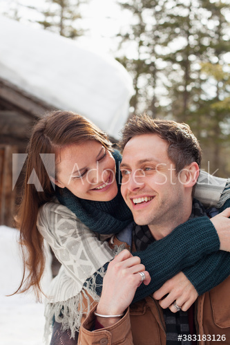 Happy affectionate couple hugging outside snowy cabin
