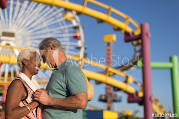 Happy affectionate senior couple at sunny amusement park