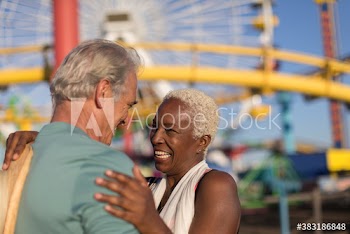 Happy affectionate senior couple hugging at amusement park