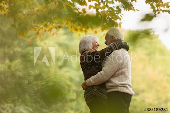 Happy affectionate senior couple hugging in autumn park