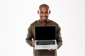Happy african man showing blank laptop computer screen and looking Free Photo