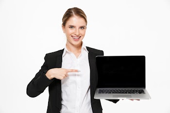 Happy blonde business woman showing blank laptop computer screen and pointing at him while  over white wall Free Photo