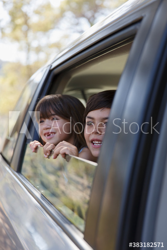 Happy brother and sister leaning out car window