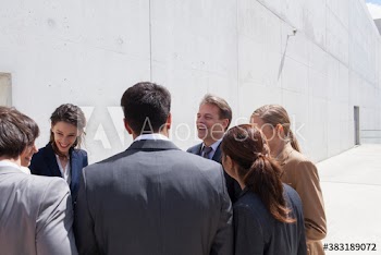 Happy business people talking in circle on sunny rooftop