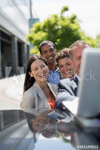 Happy business people using laptop on car