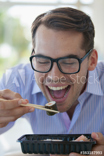 Happy businessman eating sushi with chopsticks