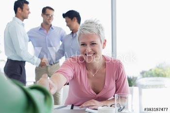 Happy businesswoman shaking hands with colleague in meeting