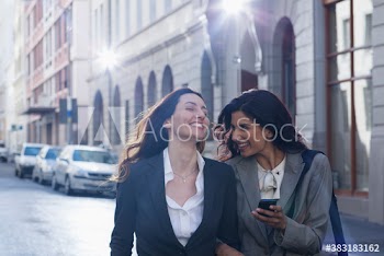 Happy businesswoman with smart phone on city street