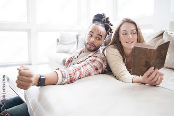 Happy couple at home together reading a book and relaxing