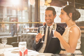 Happy couple drinking champagne celebrating engagement in restaurant