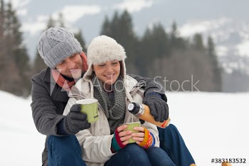 Happy couple drinking hot coffee in snow