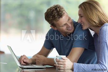 Happy couple drinking tea and using laptop