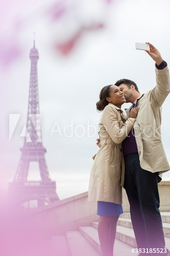 Happy couple kissing and taking selfie in front of Eiffel Tower, Paris
