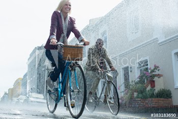 Happy couple riding bicycles on rainy street
