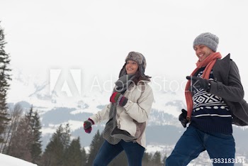Happy couple running below sunny mountain