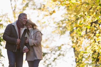 Happy couple walking arm in arm in autumn park